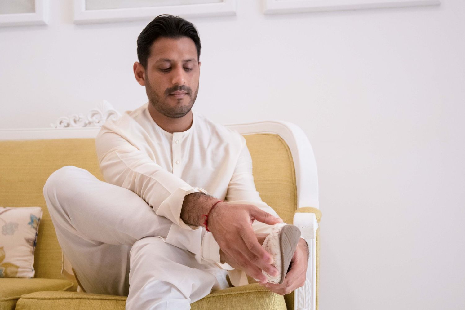 A person in a white sweater sits comfortably on a sofa while using their mobile phone.