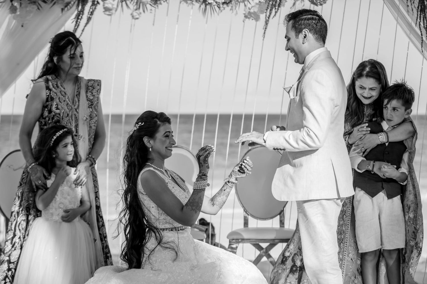 Black and white beach wedding ceremony with white decorative arch.