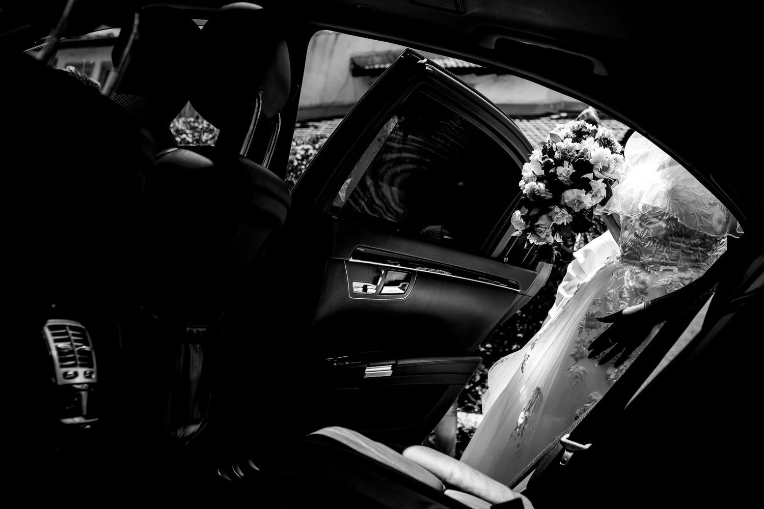 Dark silhouette of a bride entering a vehicle on her wedding day.