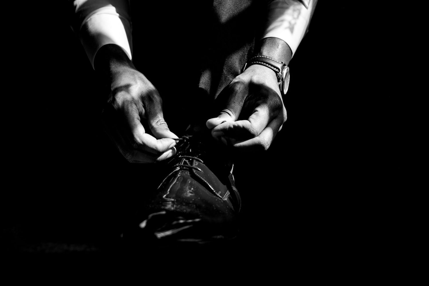 Dramatic black and white close-up of hands handling a bow tie.