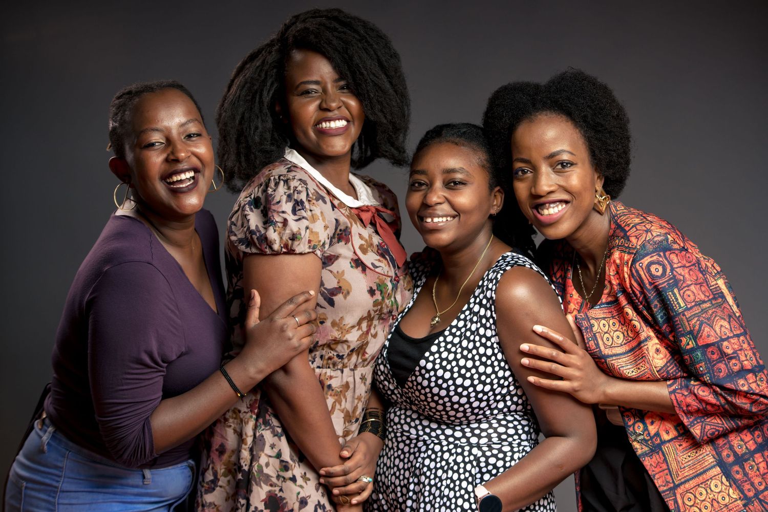 Studio group portrait showing multiple people embracing and laughing together.