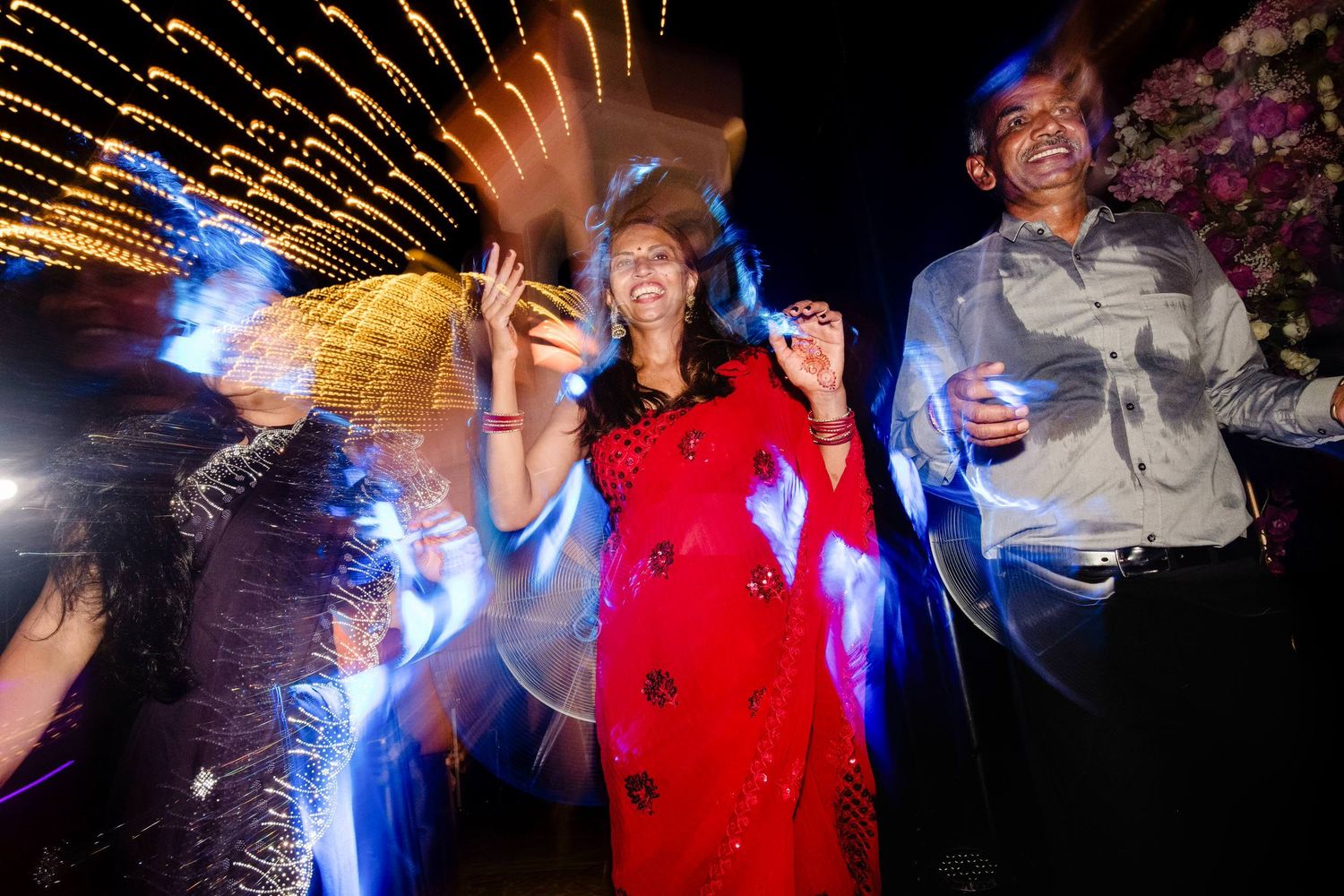 People dancing and celebrating at a lively party with colorful lights and motion blur effects.