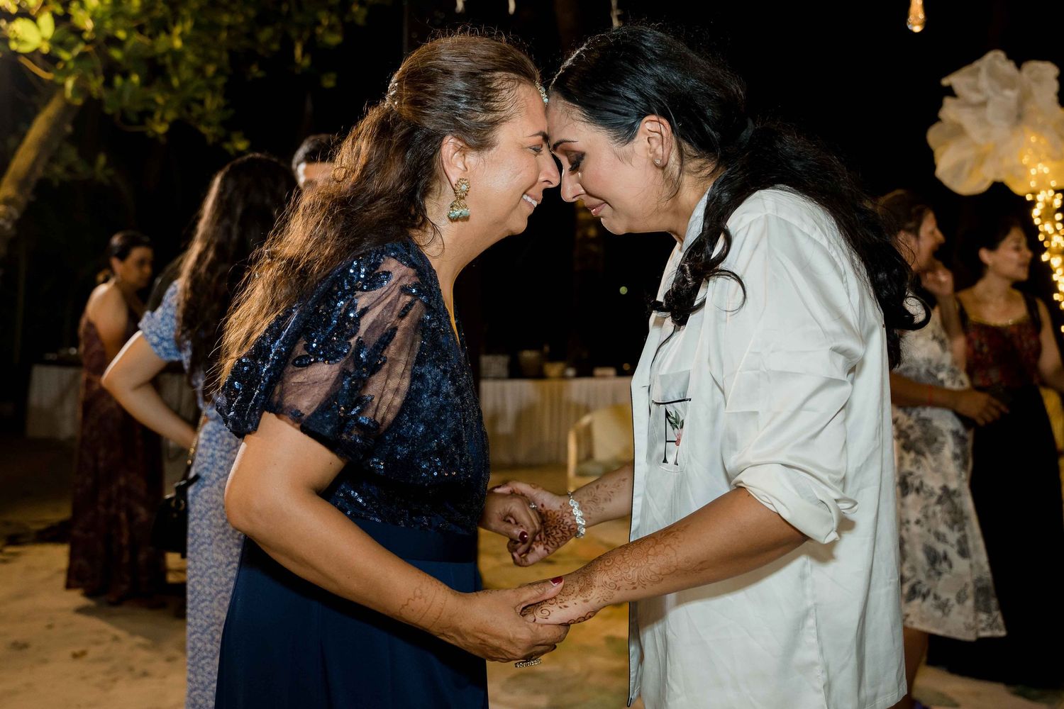Two people share an intimate moment while dancing together at a nighttime outdoor event.