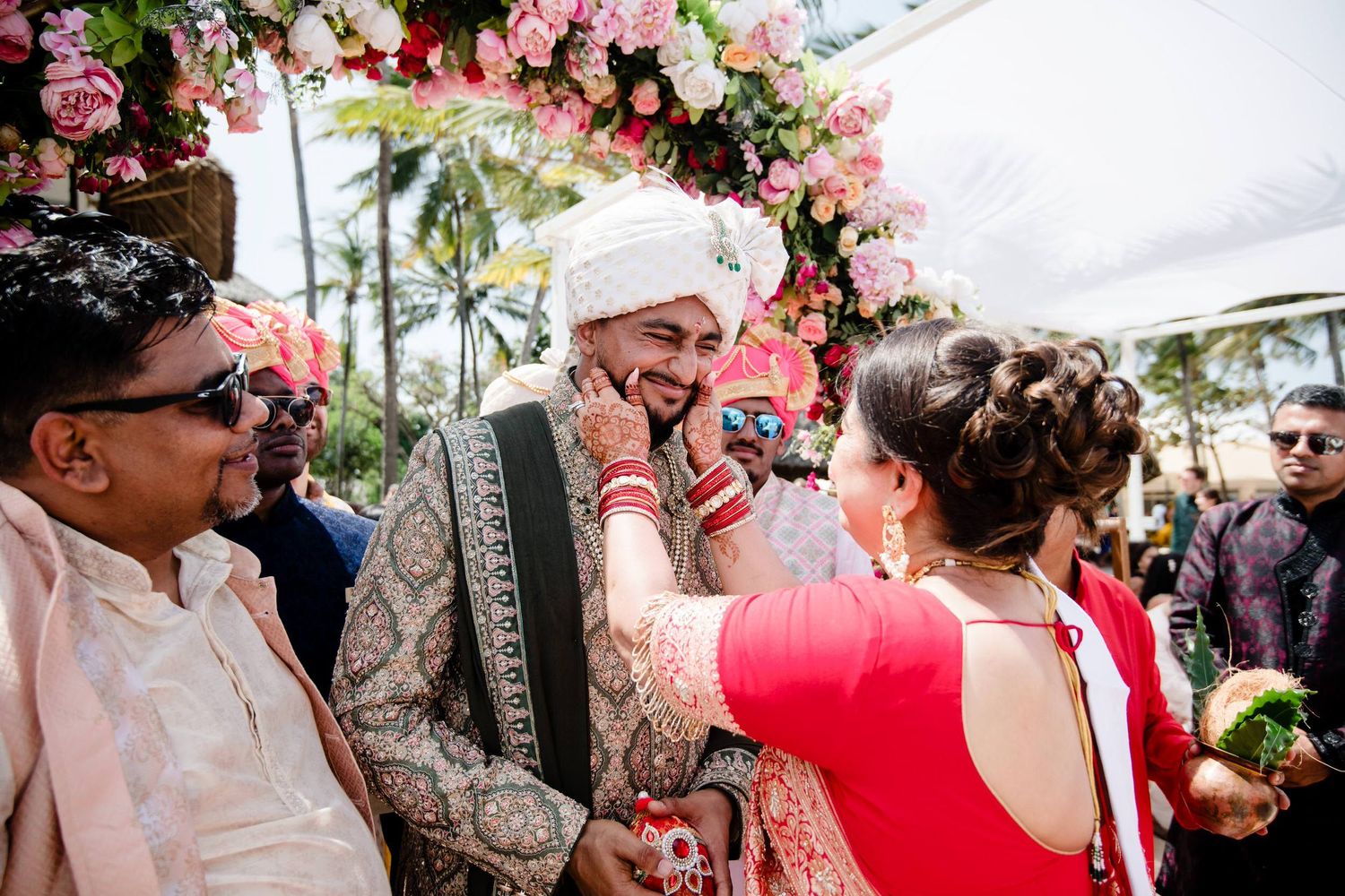 Guests gather under pink floral decorations at an elegant outdoor wedding celebration.