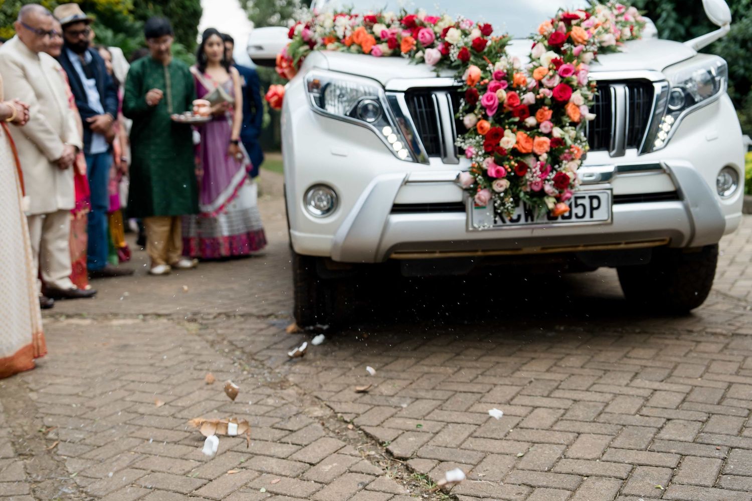 Decorated silver SUV with floral arrangements at a wedding ceremony.