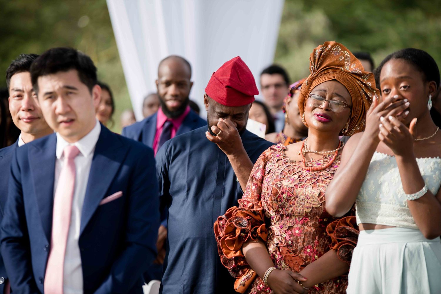 Wedding guests react emotionally during an outdoor ceremony.