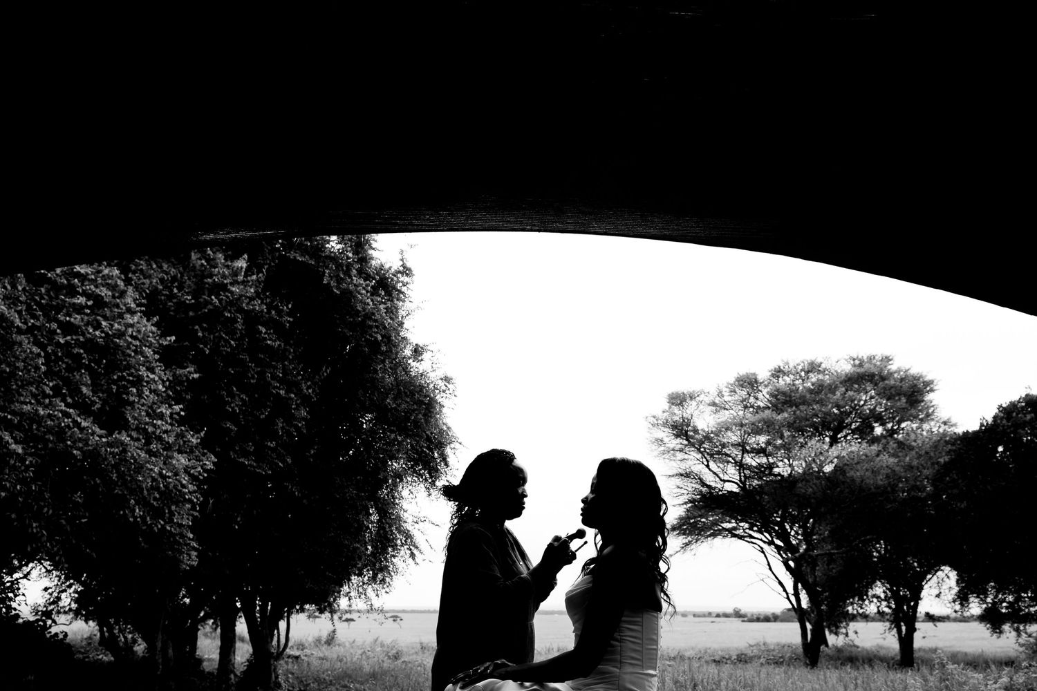 Silhouetted figures framed within an archway against a natural landscape.