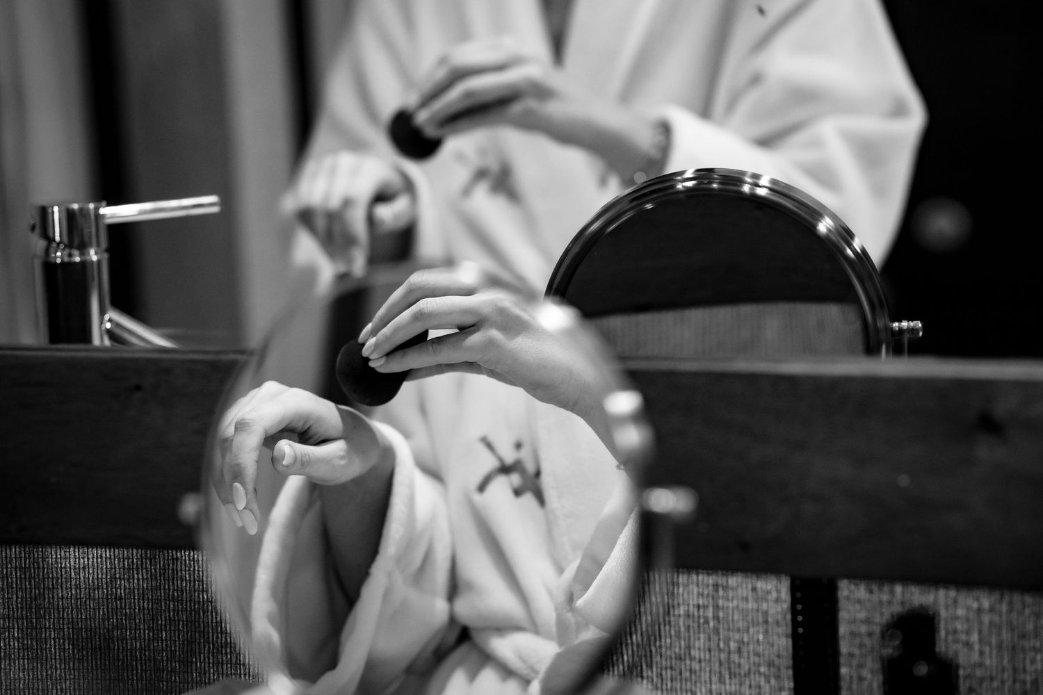 Black and white close-up of hands preparing food in a professional kitchen.