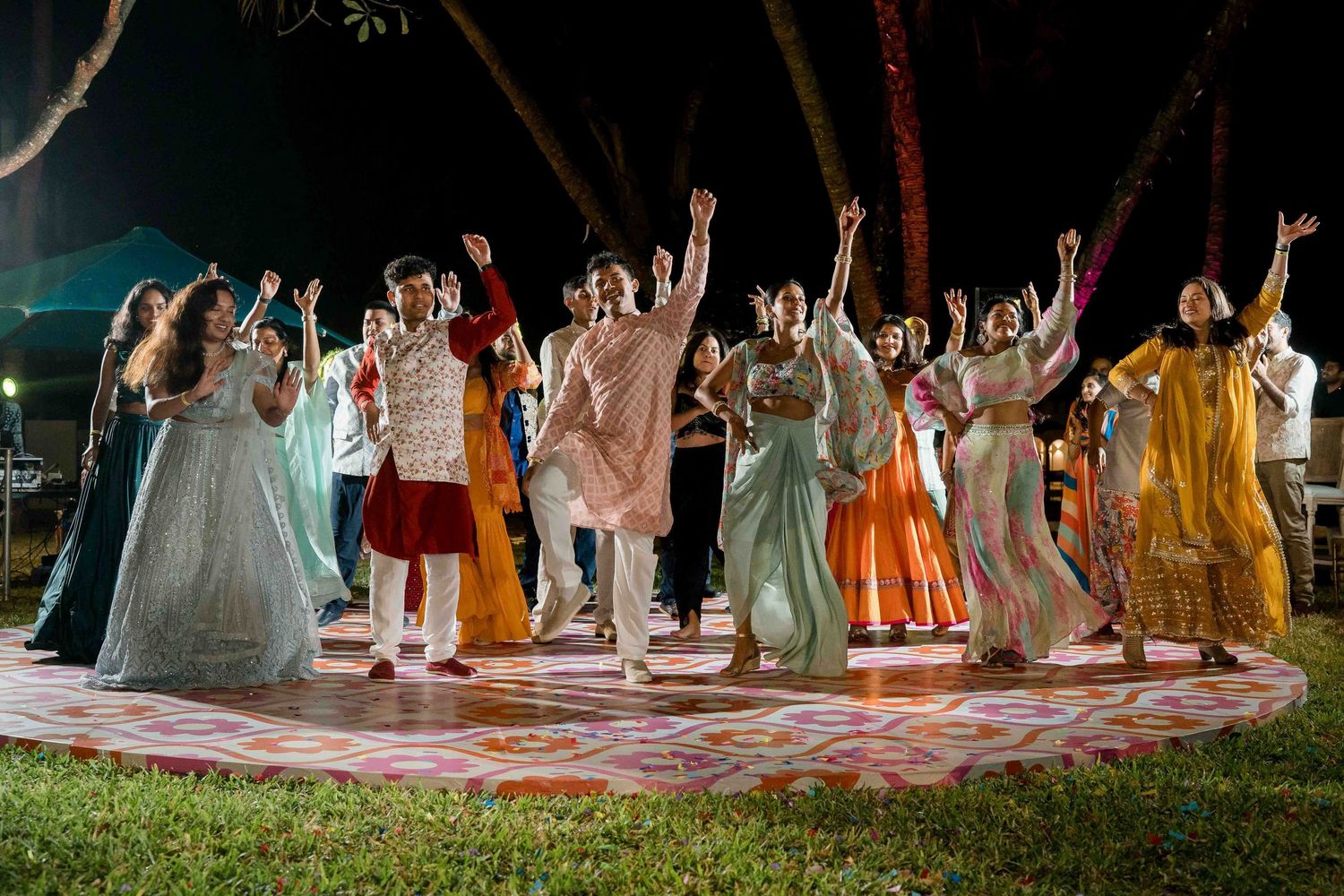 Wedding party members line up in colorful dresses and suits during an outdoor celebration.