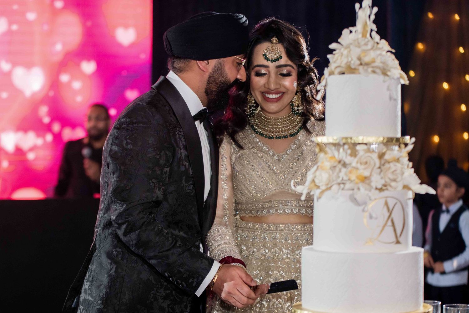 An elegant multi-tiered white and gold wedding cake on display at a reception.