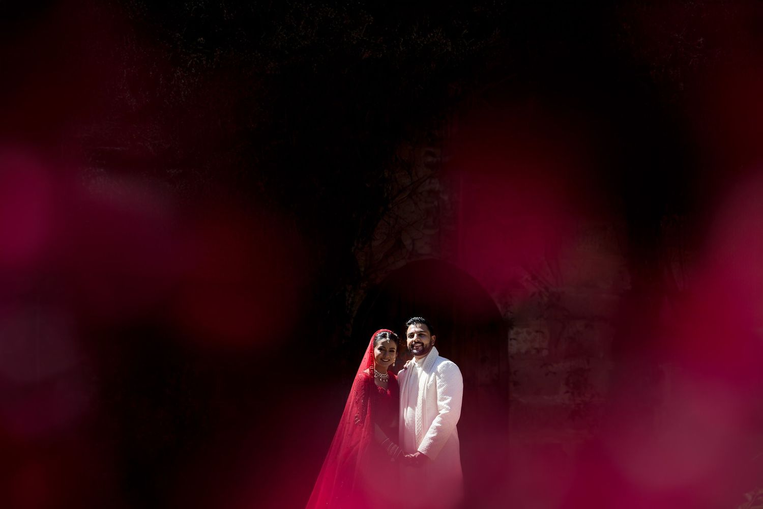 A couple poses for a dramatic wedding photo with pink smoke effects.