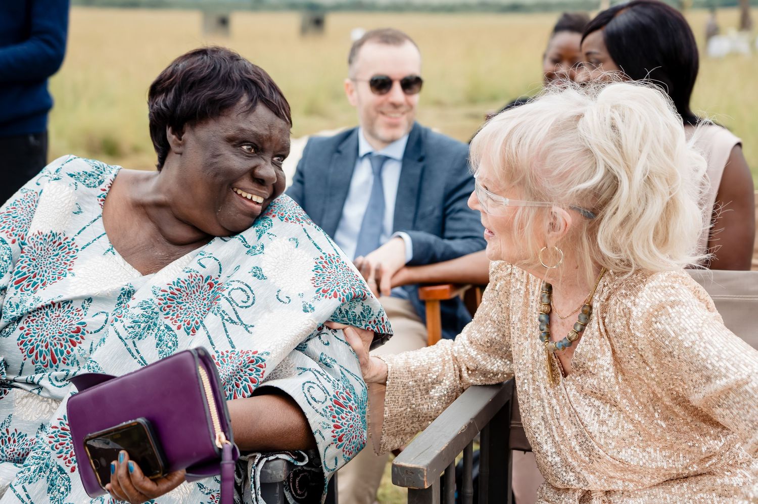 Two wedding guests share an emotional moment during outdoor celebration.