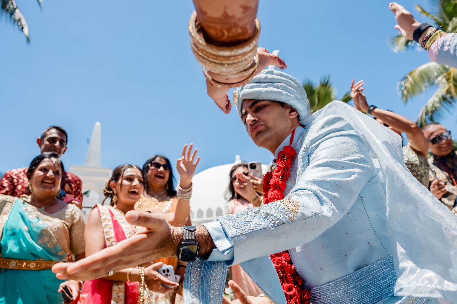 Joyous celebration with guests cheering during an outdoor tropical wedding event.