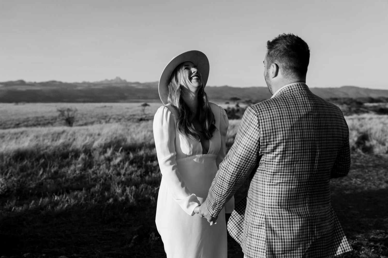 A black and white portrait of a couple in a scenic mountain landscape.