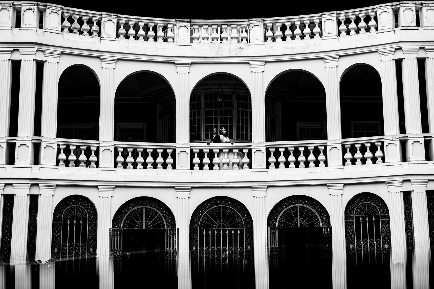 Classical white colonial architecture with symmetrical arches and balustrades in black and white.