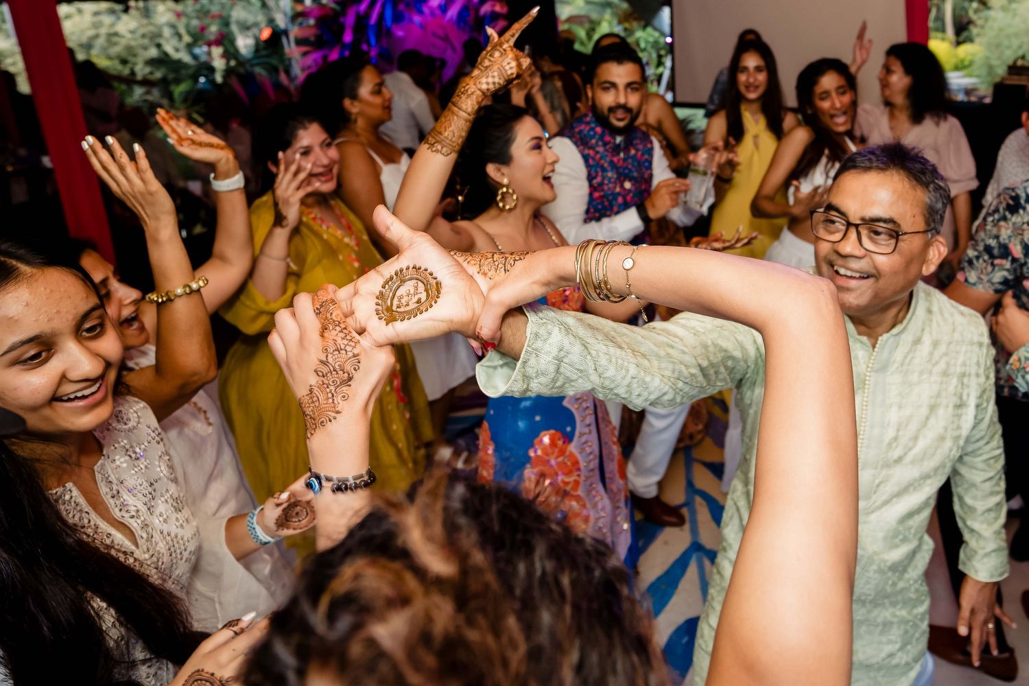Energetic crowd dancing and celebrating with hands raised during a festive party.