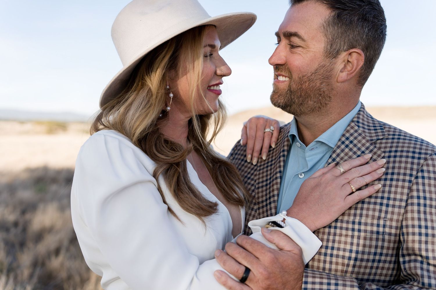 Couple sharing a joyful moment in western wedding attire against a desert backdrop.