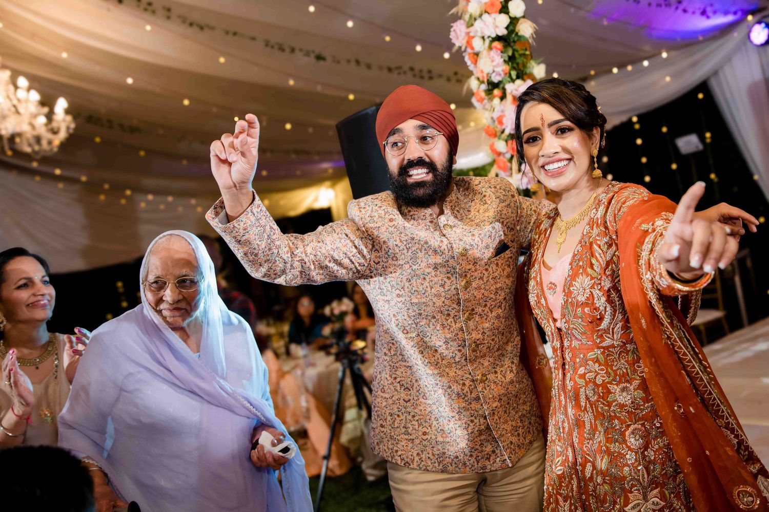 Joyful dancing celebration at a wedding reception with traditional Indian attire.