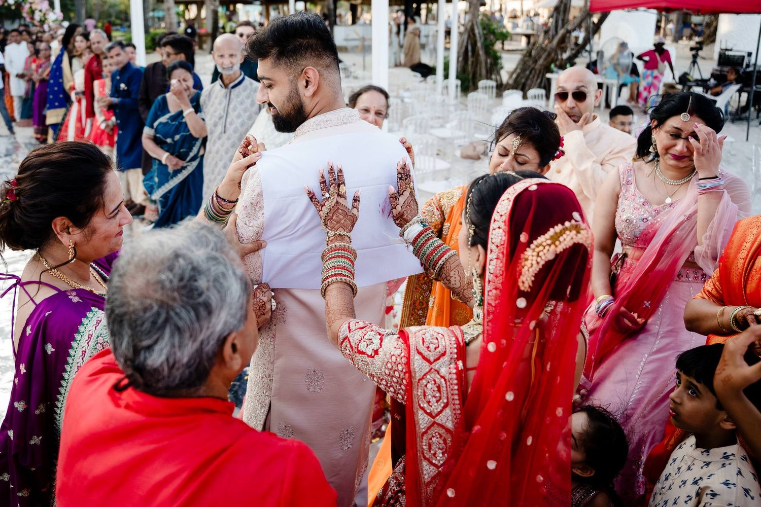 Colorful wedding celebration with guests in traditional Indian attire dancing during festivities outdoors.