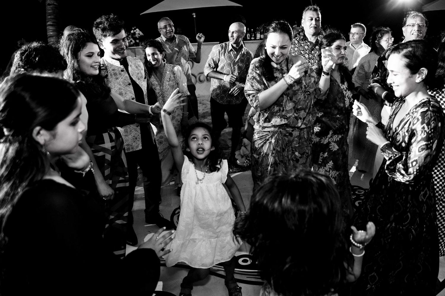 A group gathers on a dance floor at a celebration, captured in black and white photography.