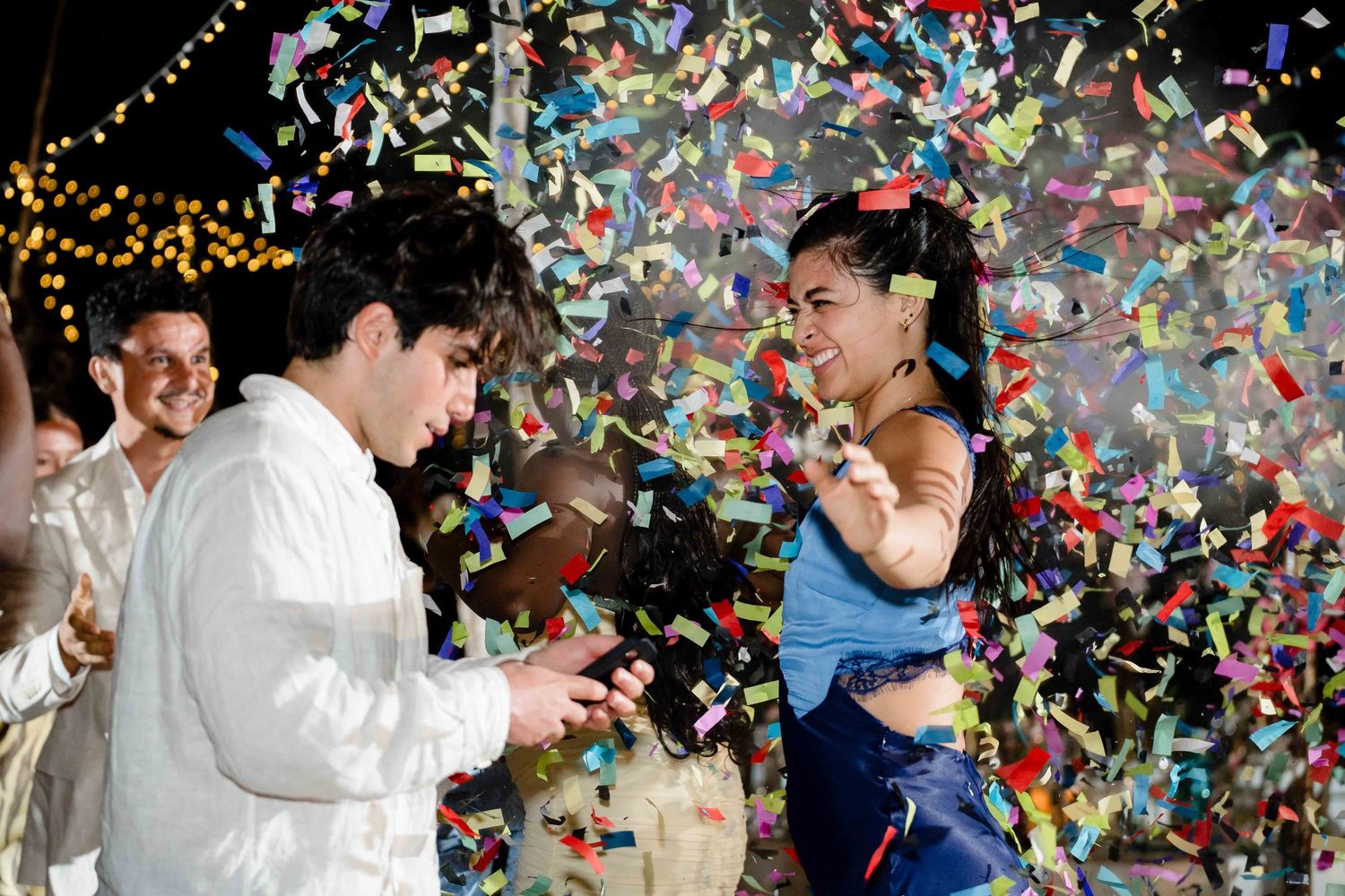 Colorful confetti rains down on a dancing couple in formal attire at a celebration event.