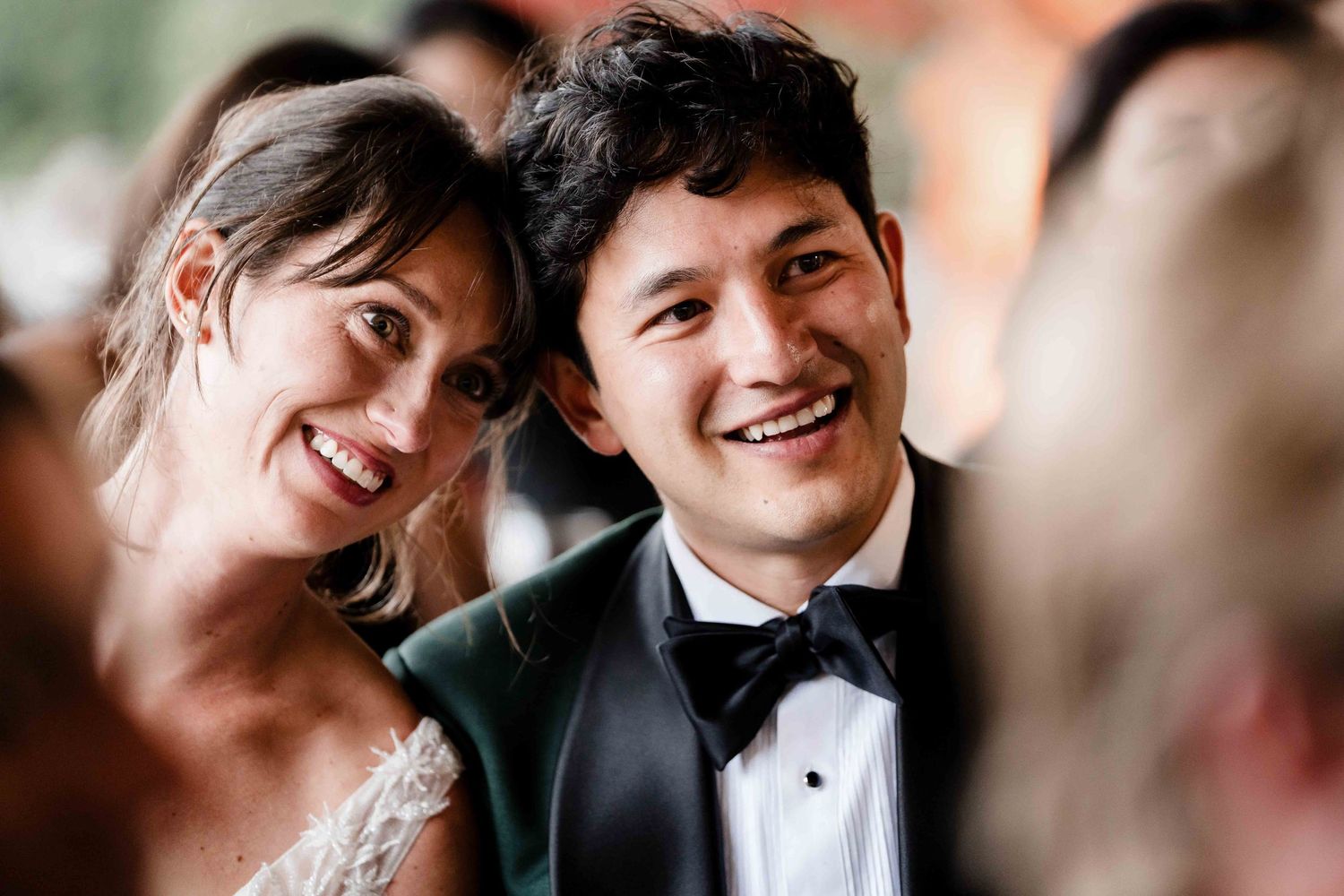 A happy couple shares a joyful moment together at a formal event, both wearing elegant wedding attire.