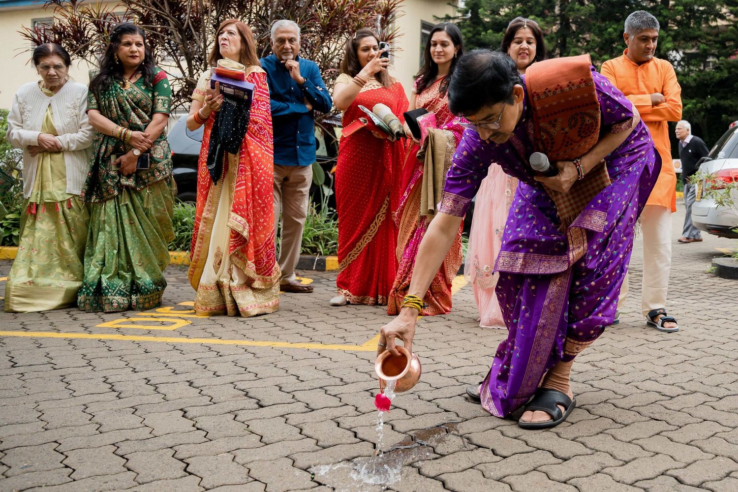 Group in traditional Indian attire performs fun game with coconut during wedding festivities.
