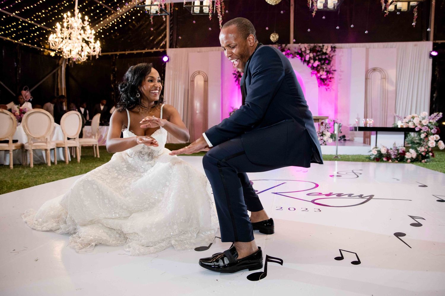 Joyful dance moment on white monogrammed dance floor at wedding reception.