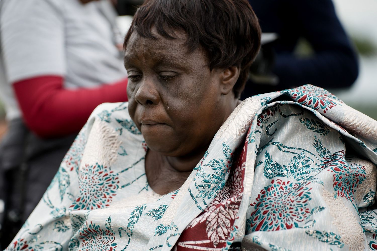 Guest wrapped in patterned blanket shows emotion during outdoor wedding.