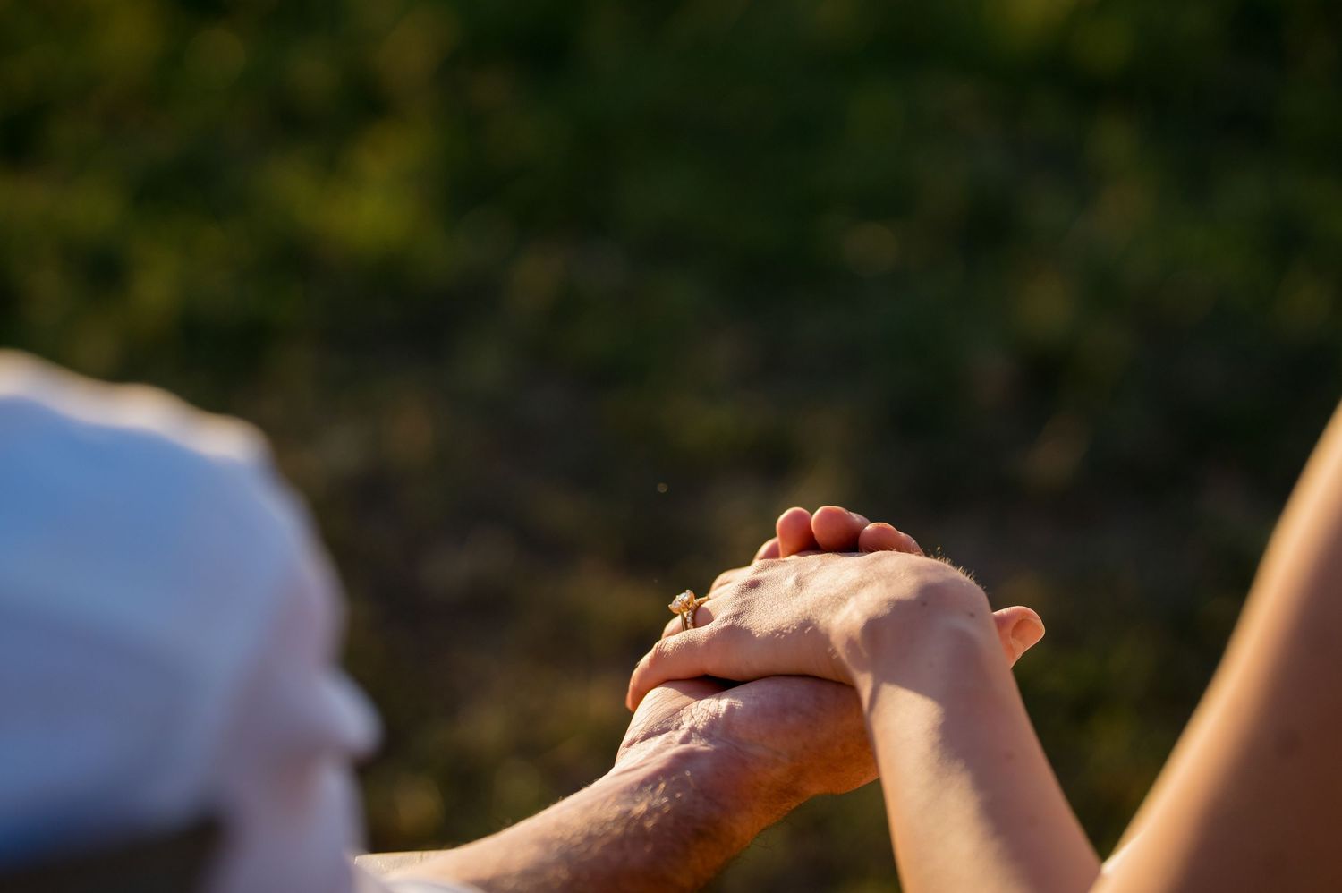 Close-up shot of clasped hands during a wedding ceremony at sunset.