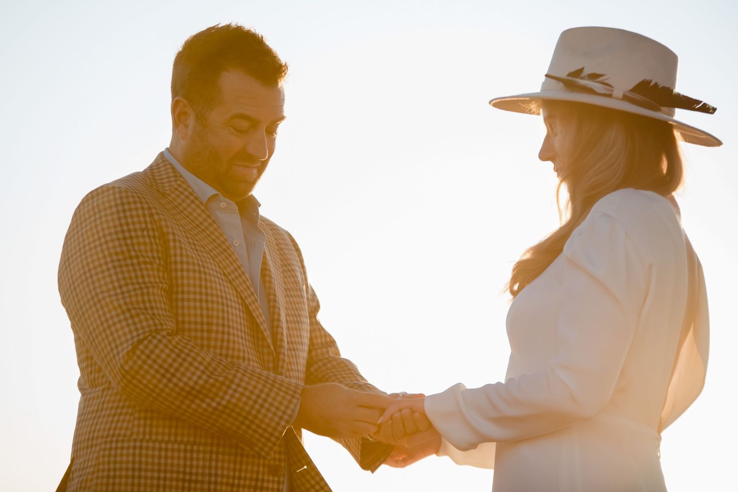 Two people in western attire shaking hands during a ceremony at golden hour.