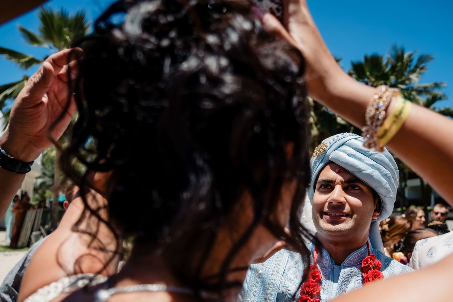 Joyful celebration during an outdoor wedding ceremony with guests smiling beneath palm trees.