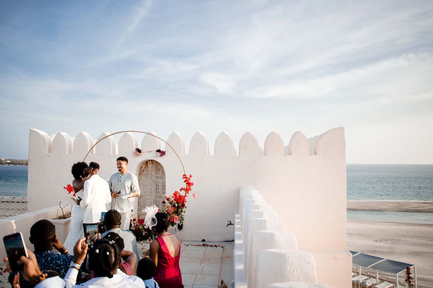 A collection of beachside wedding ceremony photos showing white decor, ocean views, and celebratory moments.