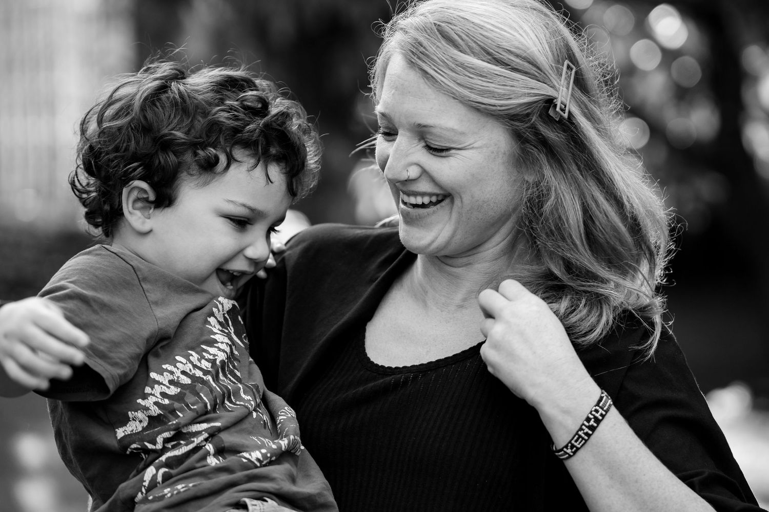A mother and young child share tender moments of laughter and affection in a black and white photo series.