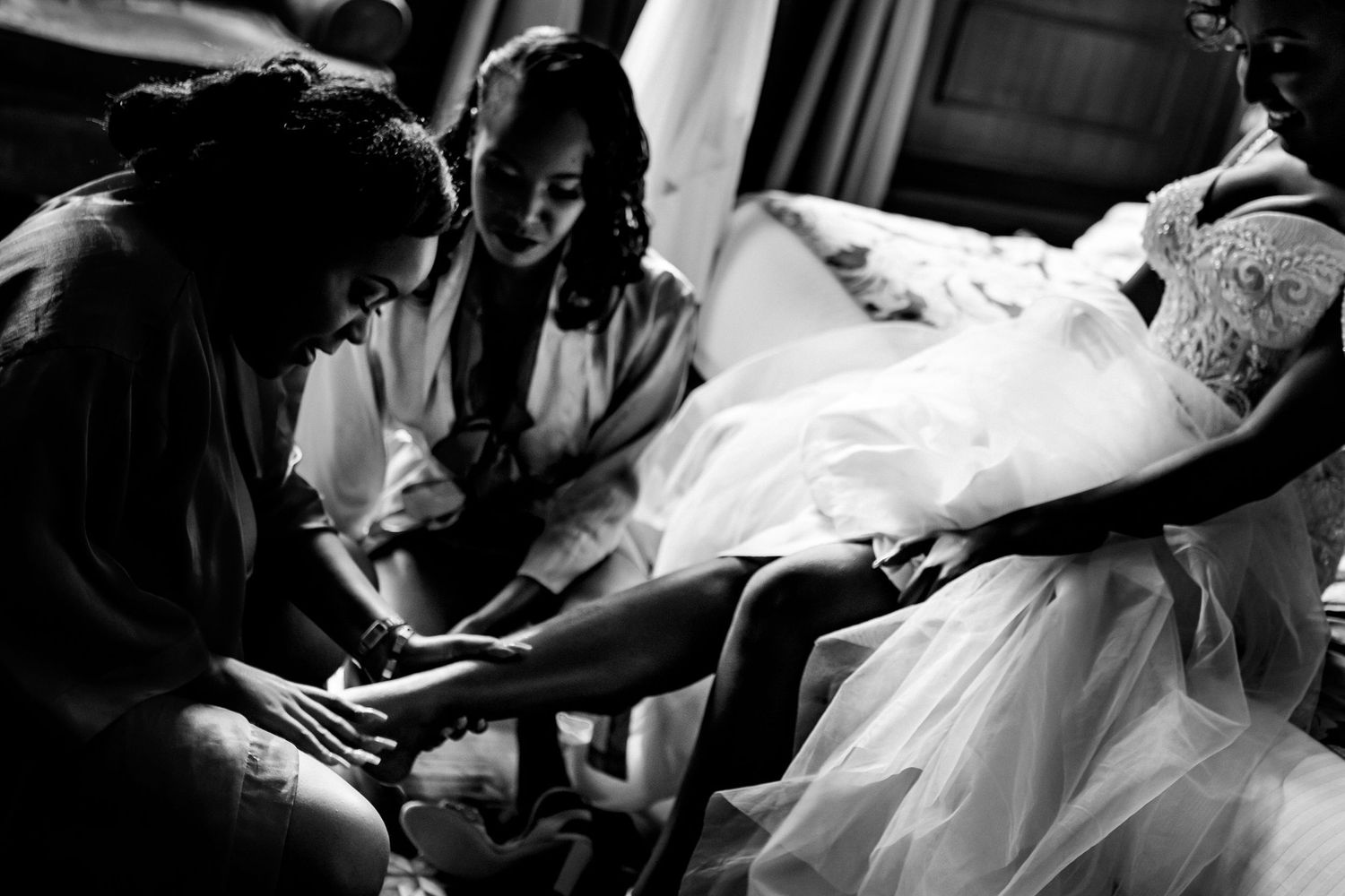 Black and white candid shot of wedding dress preparation and final adjustments.