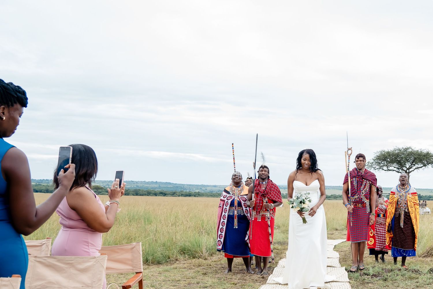 Wedding ceremony on African plains with traditional local dancers in bright attire.