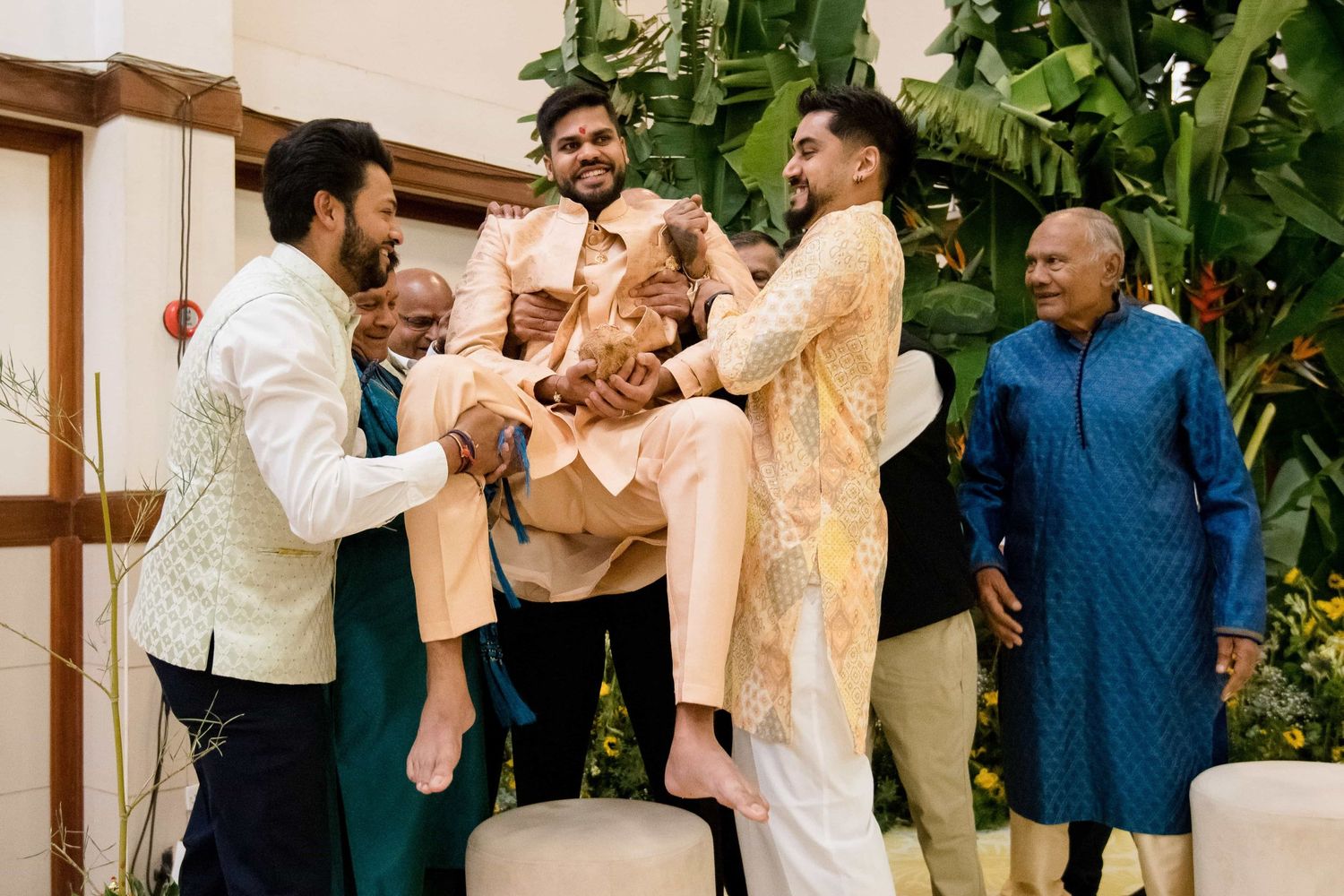 Celebratory moment during an Indian ceremony with participants in traditional cream-colored attire.