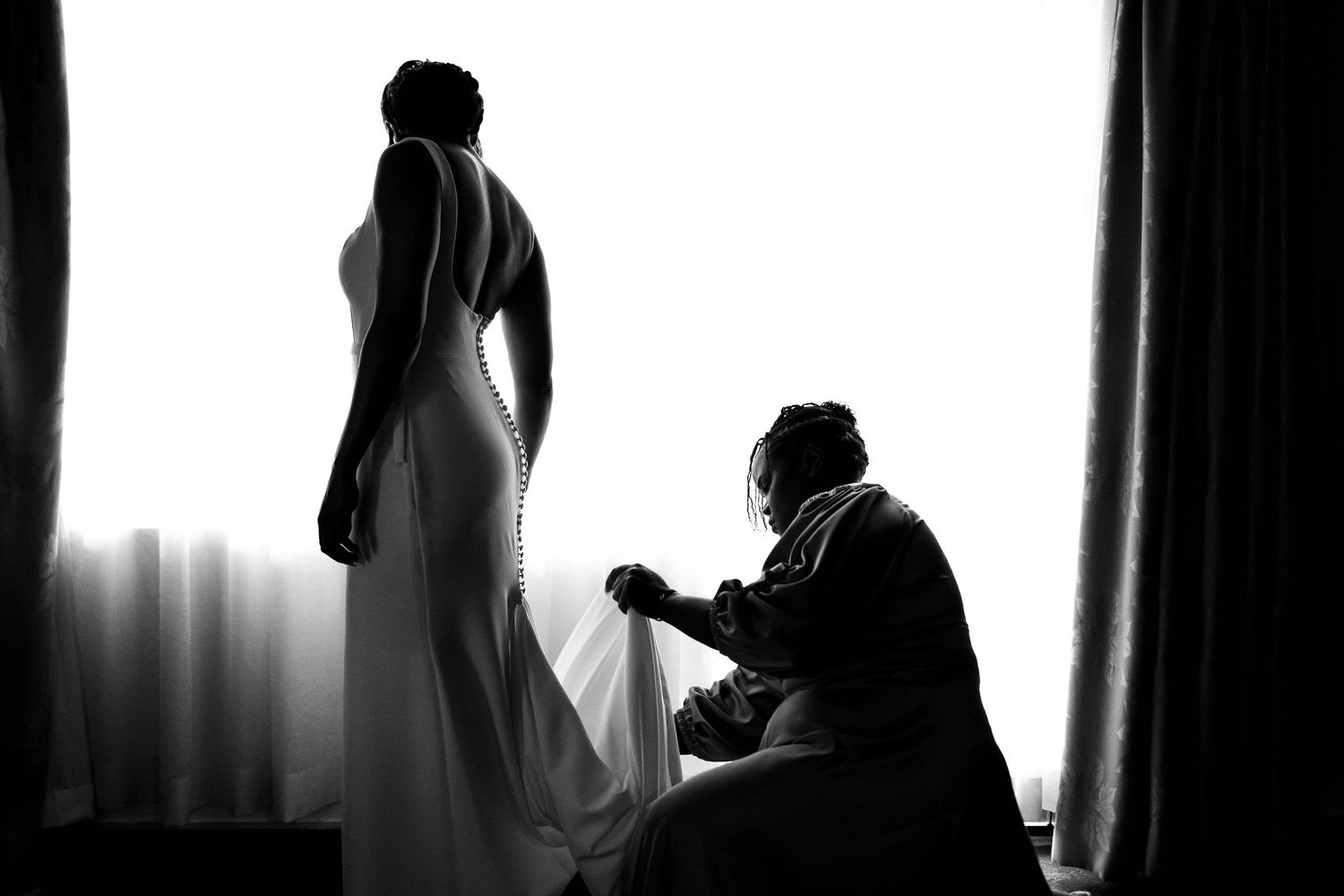 A dramatic black and white silhouette composition shows figures in shadow against bright window light.