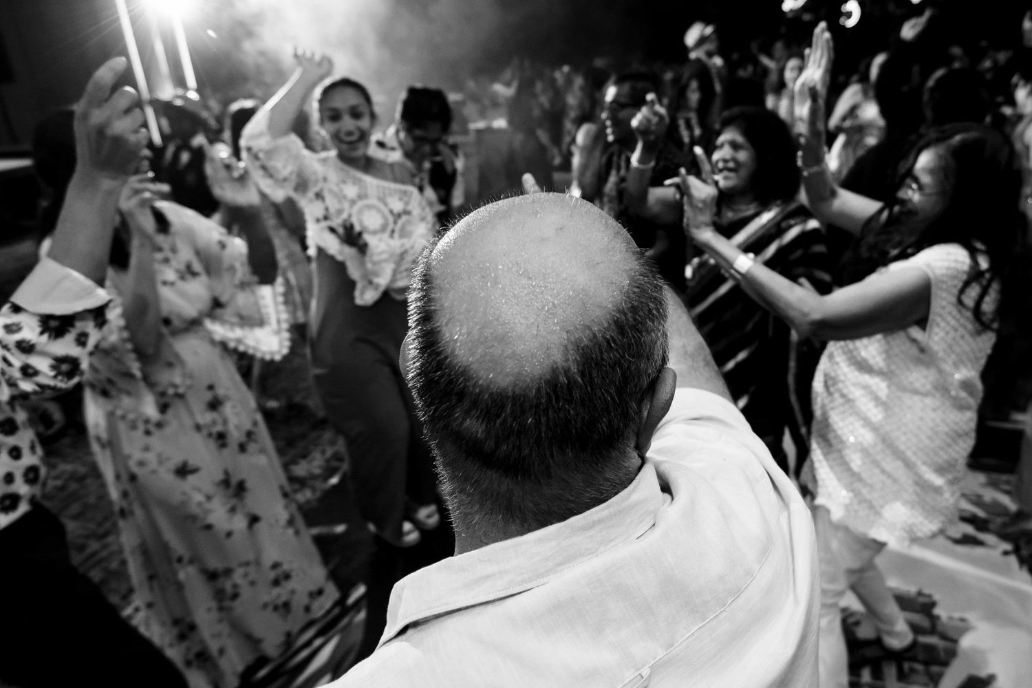 A black and white photo captures people dancing and celebrating on a crowded dance floor at night.