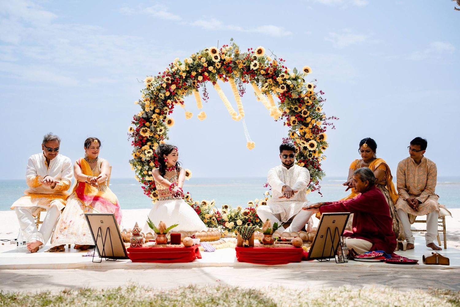 Outdoor beach wedding ceremony setup with floral arch and seating arrangements against ocean backdrop.