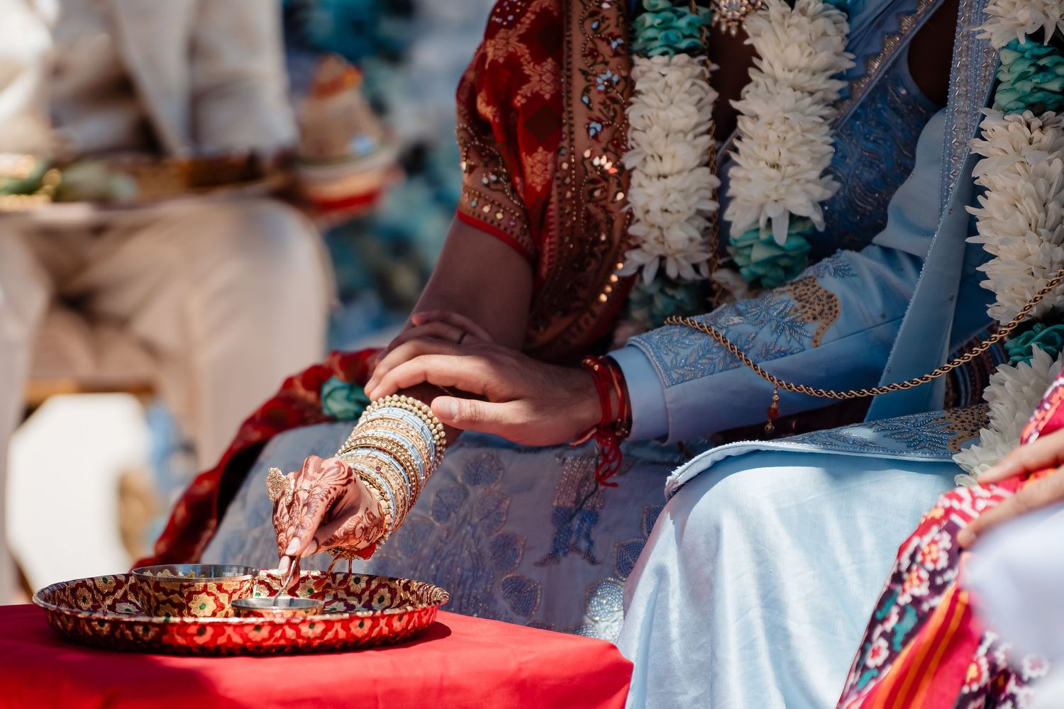 Traditional Indian wedding ritual with decorated plate and henna-adorned hands.