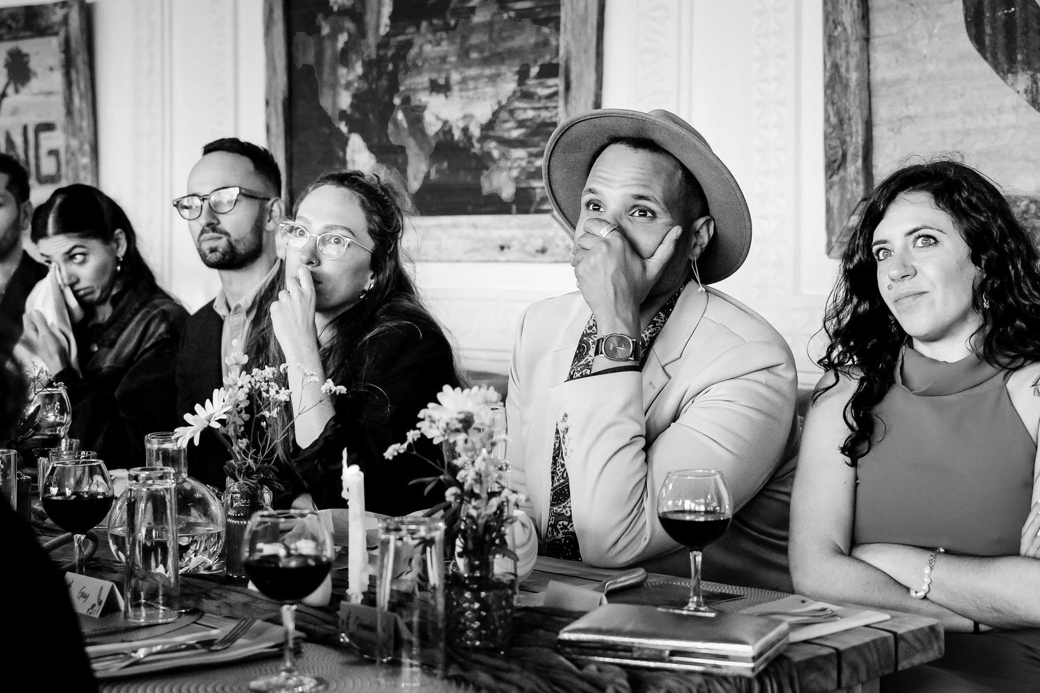 A group of friends enjoying drinks and conversation at a bar counter in a black and white photograph.