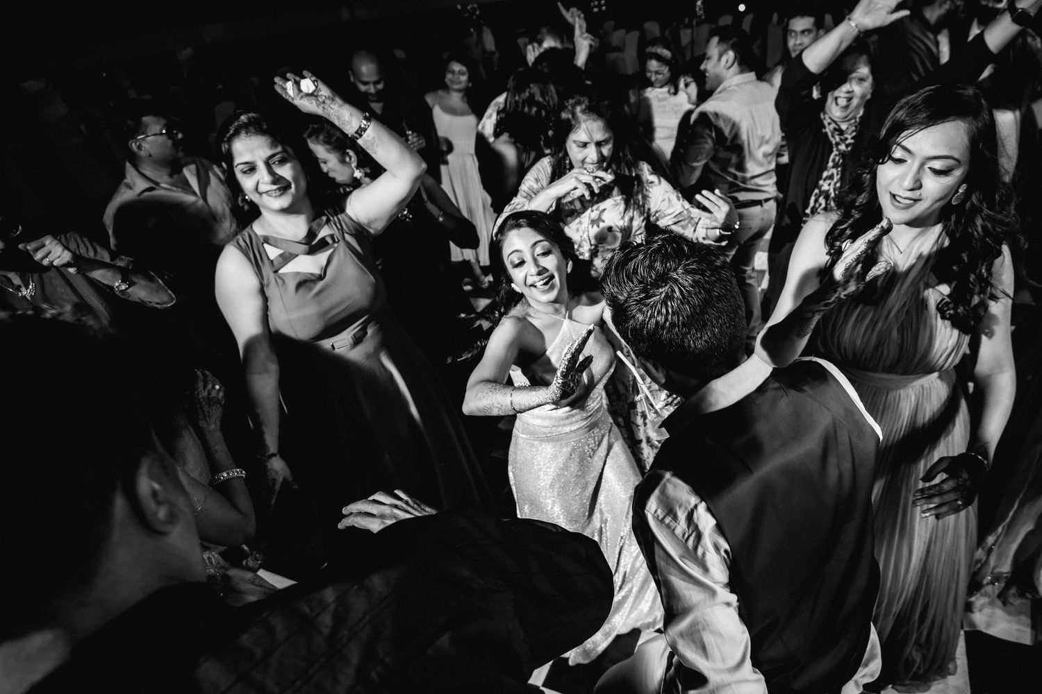Party crowd dancing and celebrating together in a dark venue with dramatic lighting.