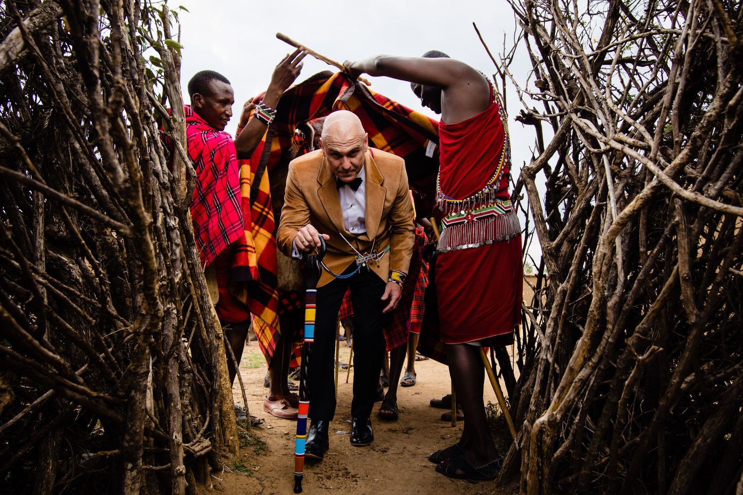 People participating in a traditional ceremony through a wooden archway.