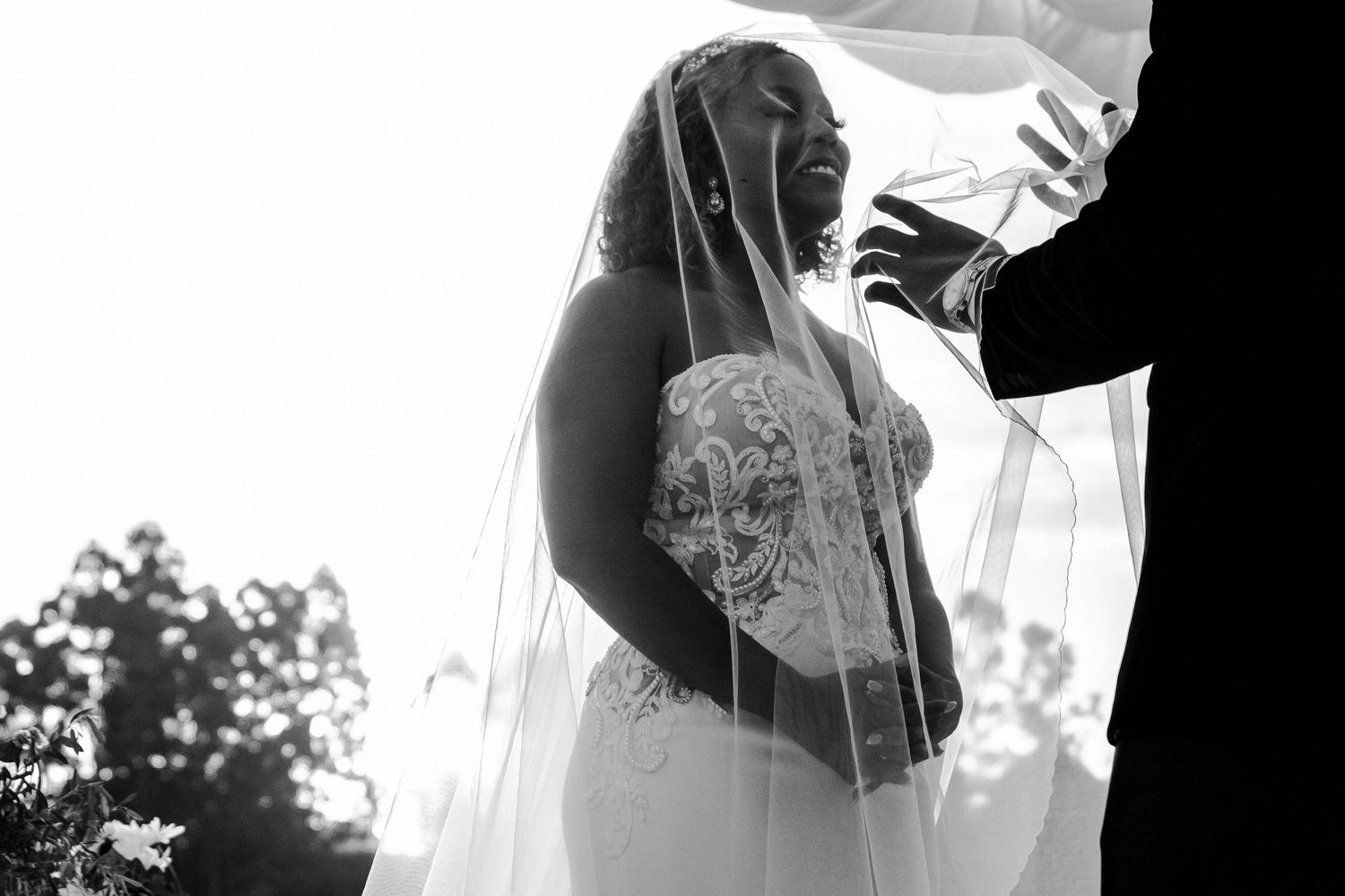 White lace and tulle details of a wedding dress flow in soft focus.