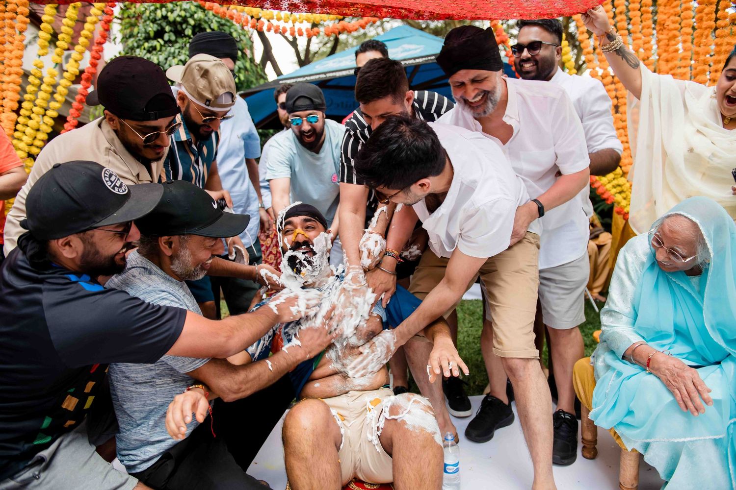Celebratory moment with guests spraying water during outdoor Indian wedding festivities.