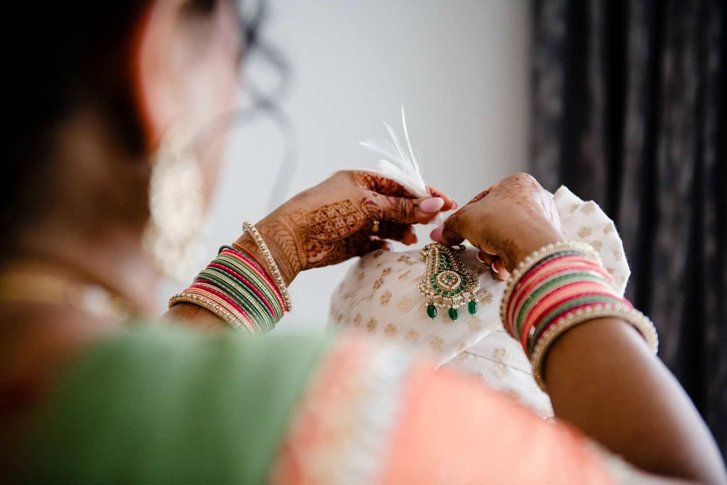 A close-up detail shot of hands wearing bangles and jewelry during a traditional Indian wedding ceremony.