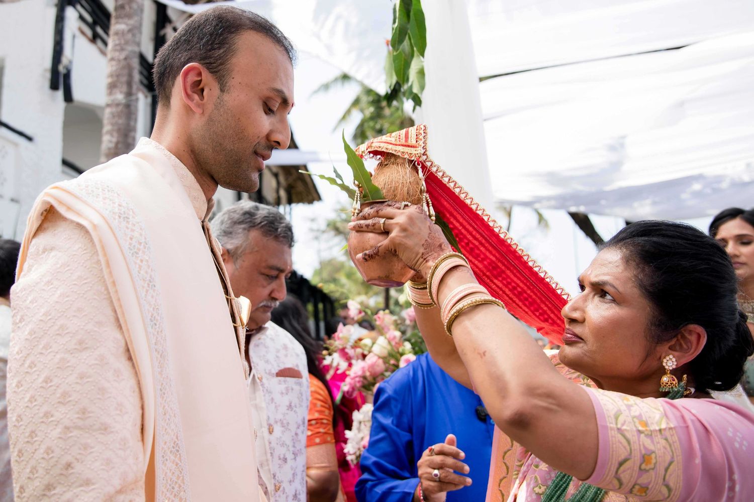 Group of people engaged in festive celebration with traditional Indian attire and rituals at a cultural event.