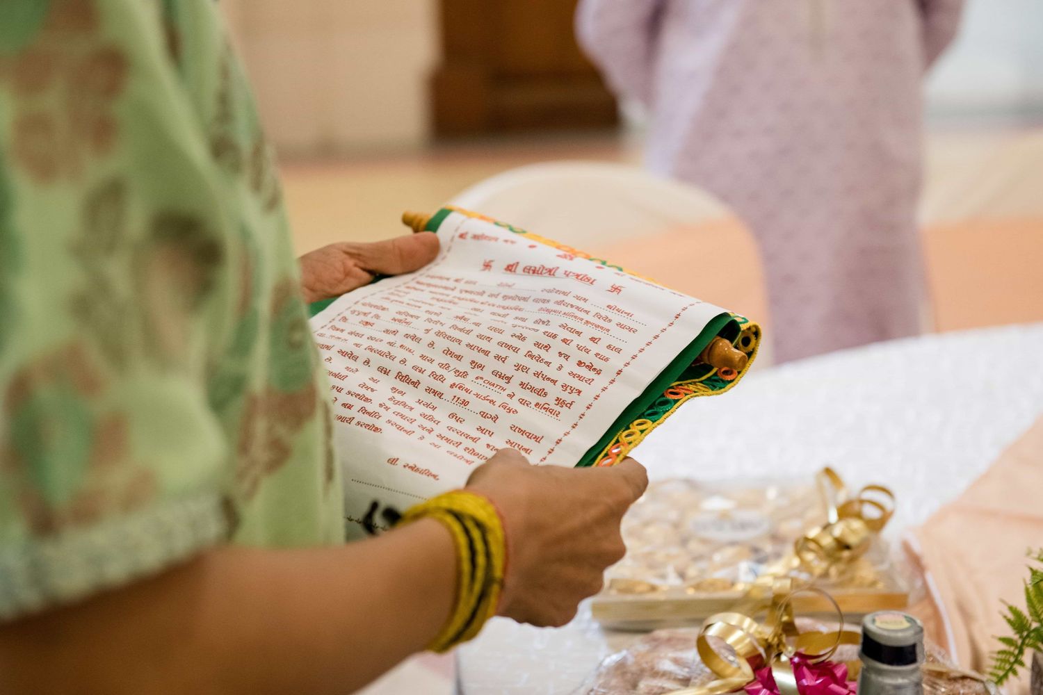 Hands holding traditional wedding documents with flowers and decorations on the table.