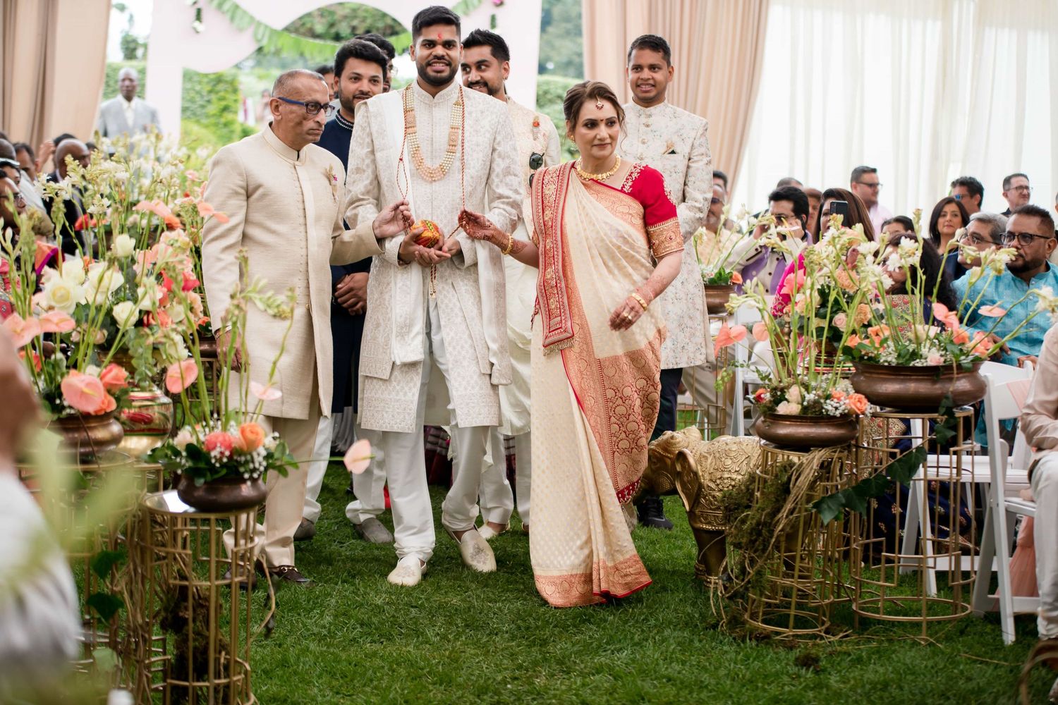 Wedding ceremony setup with elegant floral decorations and traditional elements on a garden lawn.